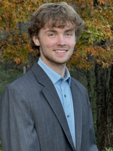 Headshot of Gavin, he is standing in front of a tree with leaves