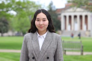 Darika stands in front of Hendricks Chapel wearing a white blouse and gray blazer