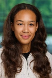 Headshot of Livia in front of a blurred background. Livia is wearing a light colored sweater